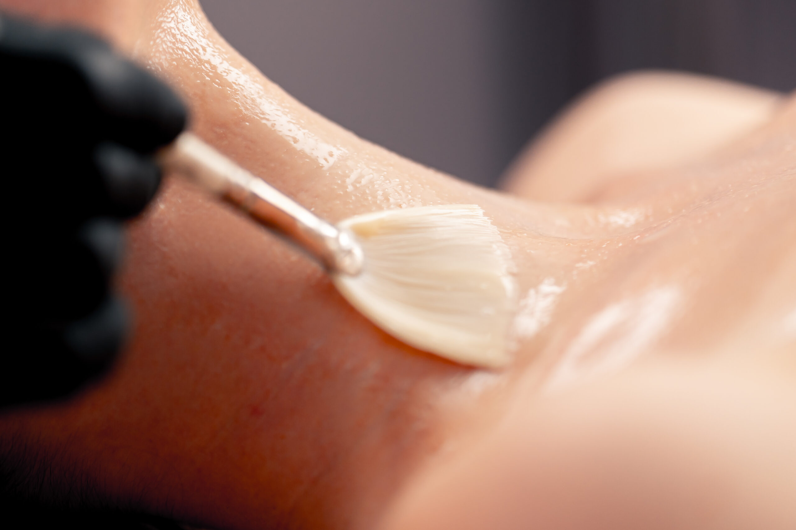 Cosmetologist applying treatment to patient neck area at Couture Dermatology